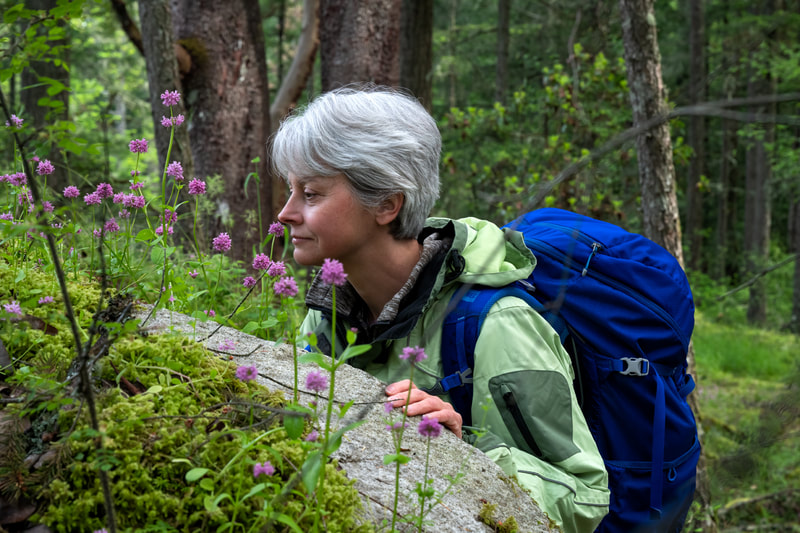 Person smelling flowers in the forest.